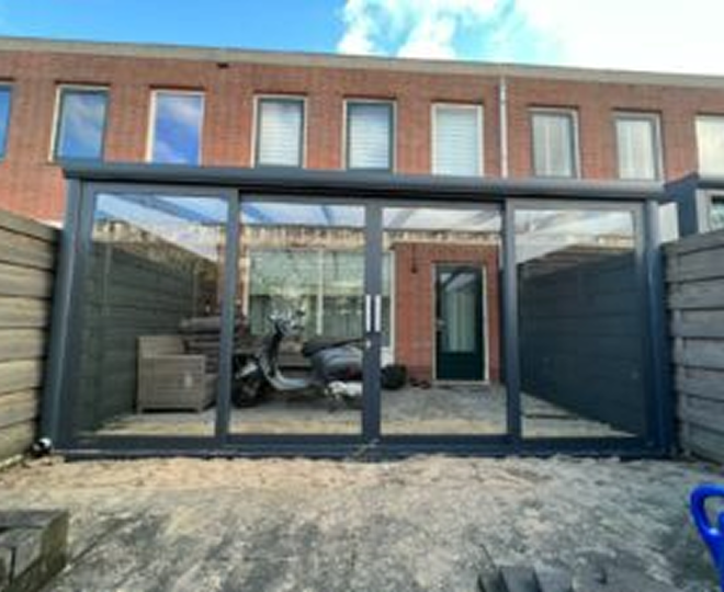 Aluminium veranda met glazen schuifwanden langs woninggevel