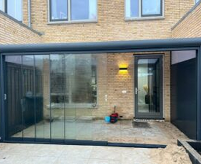 Aluminium veranda met volledig glazen schuifwanden aan achtergevel van stedelijke woning
