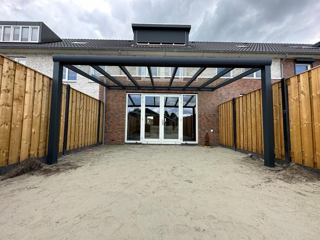 Aluminium veranda met schuifdeuren en glazen wanden aan zij- en achtergevel van woning