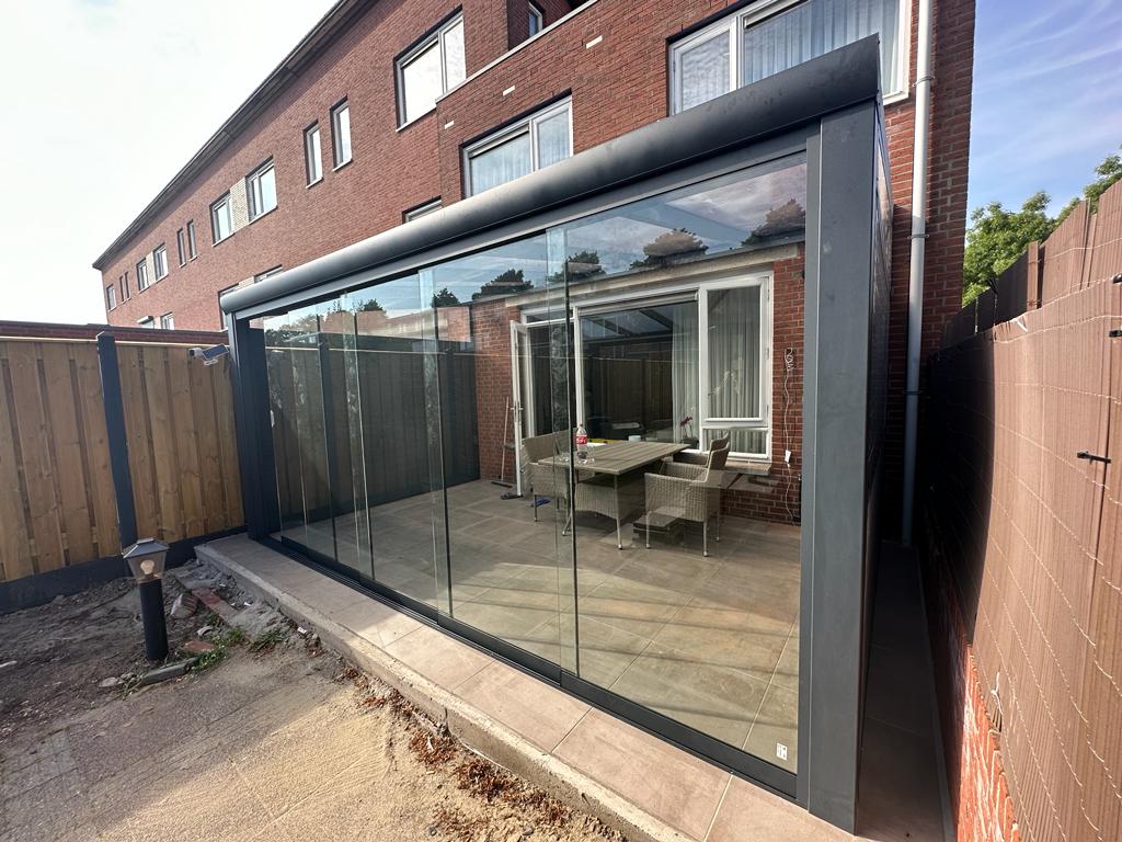 Volledig afgesloten aluminium veranda met glazen schuifwanden aan achtergevel van stedelijke woning
