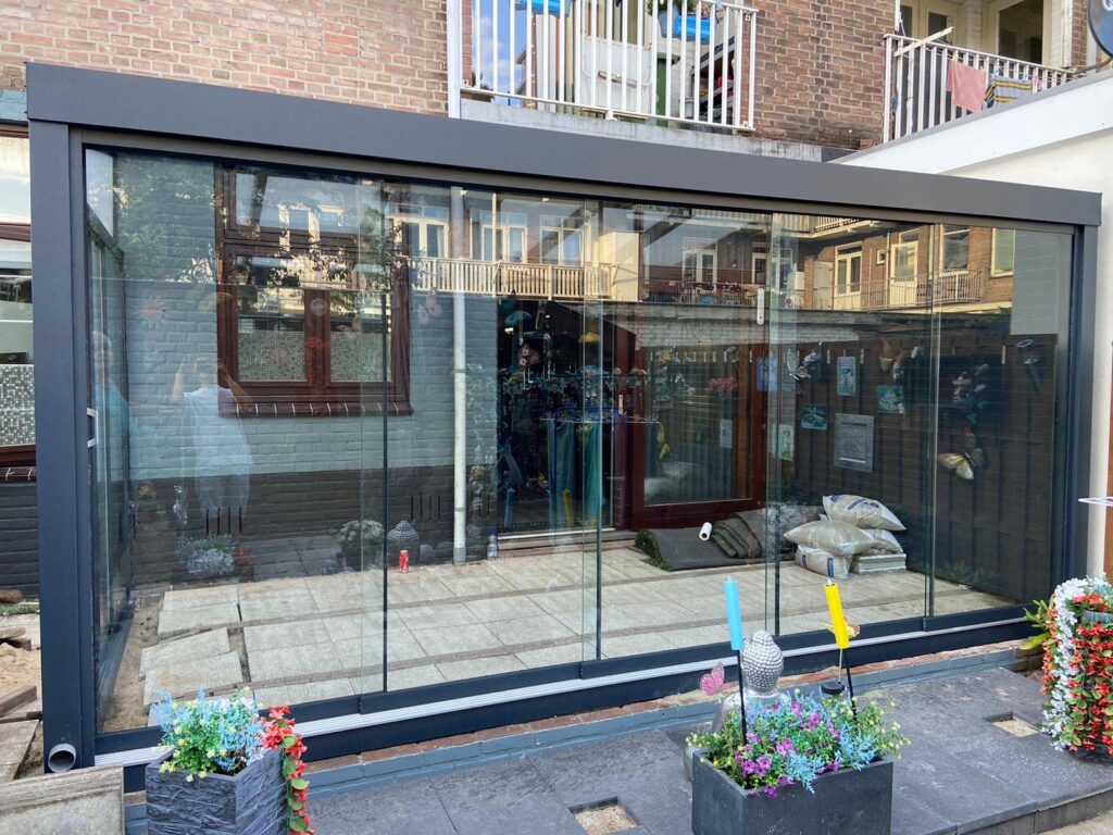 Volledig afgesloten aluminium veranda met glazen schuifwanden aan achtergevel van stedelijke woning