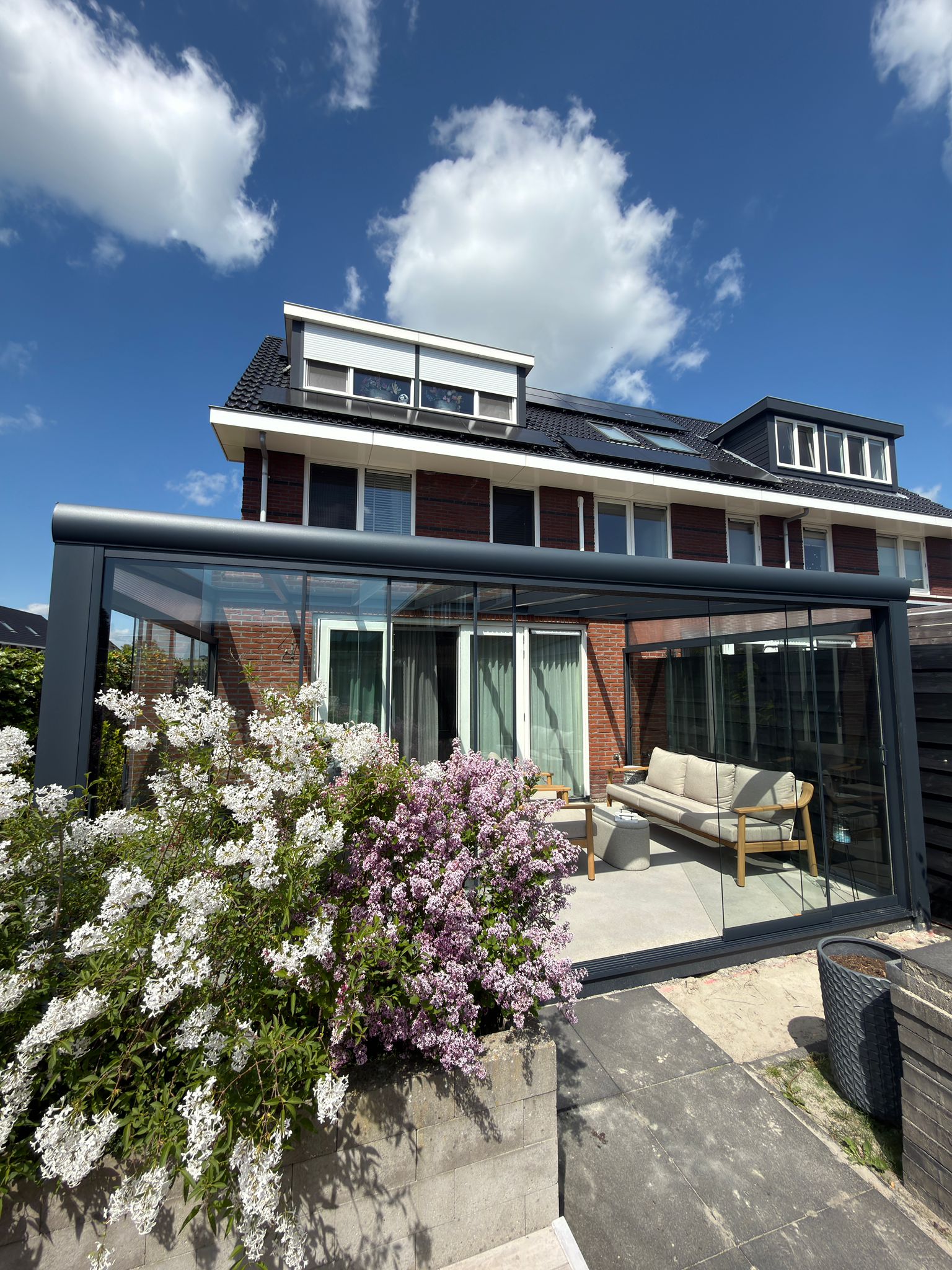 Volledig gesloten aluminium veranda met glazen schuifwanden aan achtergevel