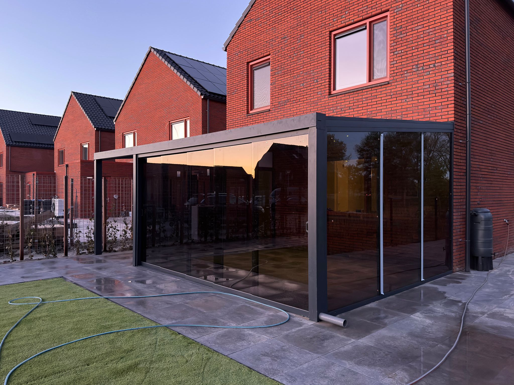 Moderne aluminium veranda met glazen schuifwanden en dichte zijwand